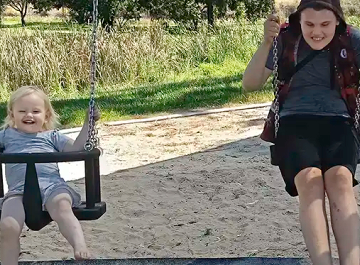 A brother and sister swing happily