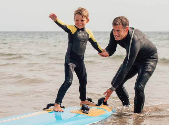 A dad helps a child surf
