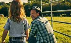 dad looks happily at child in farm agricultural setting