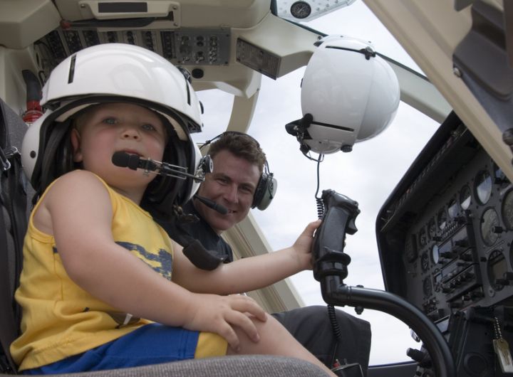 toddler sitting in passenger seat of helicopter with Dad in pilot's seat